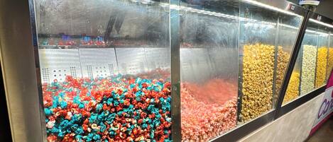 A candy display with various colors of popcorn and other snacks.