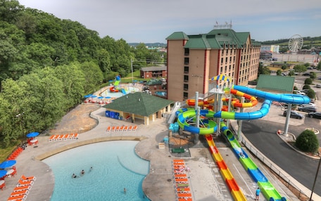 A water park with a swimming pool, water slides, and a building with a green roof.