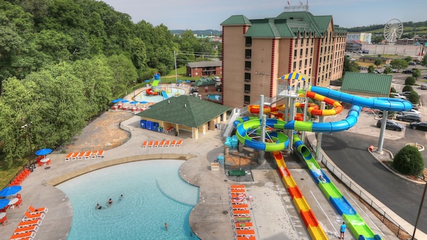 Een waterpark met een zwembad, glijbanen en een gebouw met een groen dak.