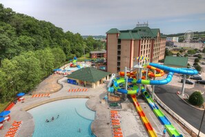 A water park with a swimming pool, water slides, and a building with a green roof.