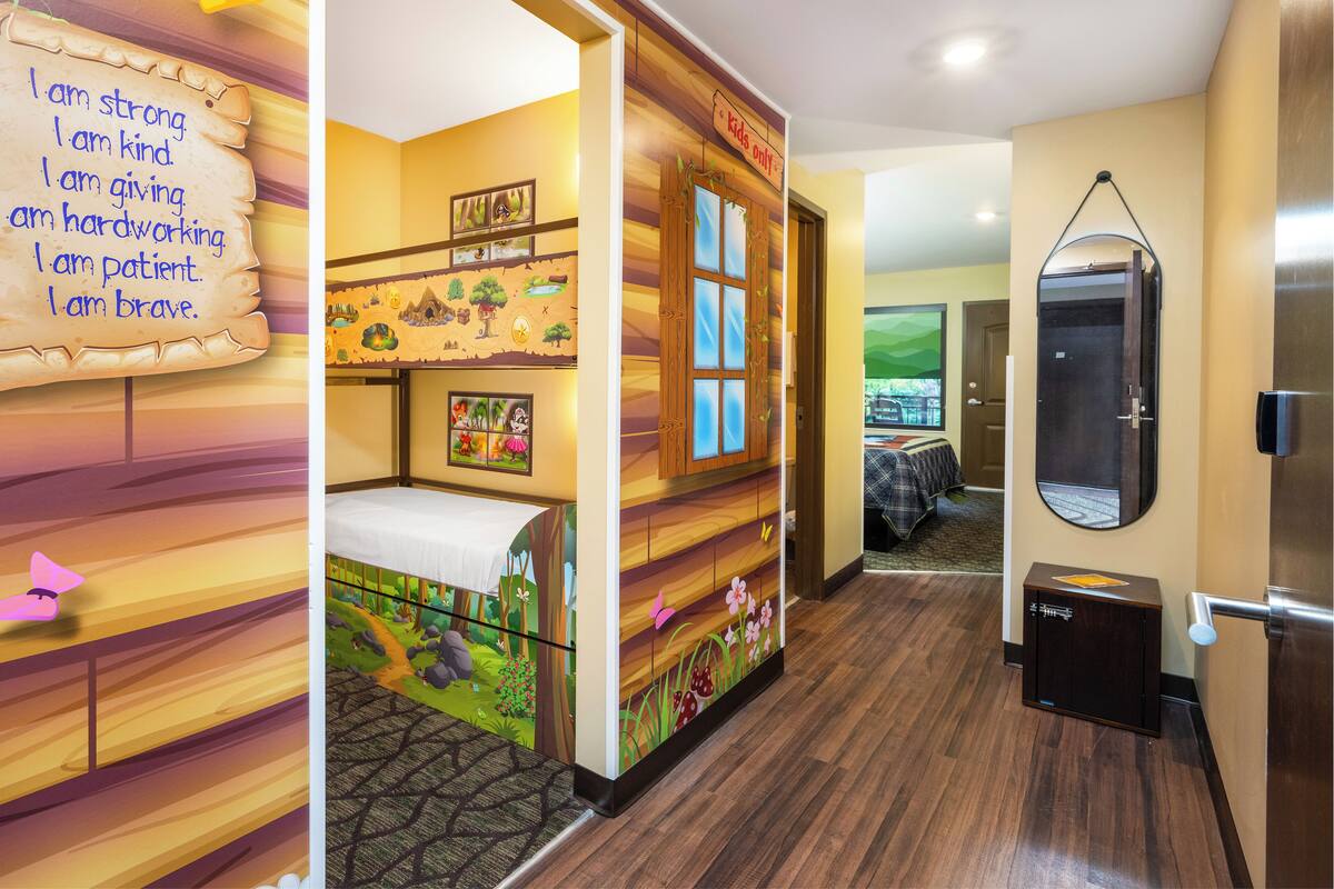 Une chambre d’enfant avec un lit superposé, un panneau indiquant « Réservé aux enfants », un miroir et une porte avec une poignée.