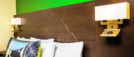 Een hotelkamer met een houten hoofdeinde, twee bedlampen en een bed met beddengoed met een patroon.