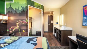 A hotel room with a bed, a desk, a mirror, and a bathroom.