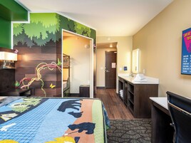 A hotel room with a bed, a desk, a mirror, and a bathroom.