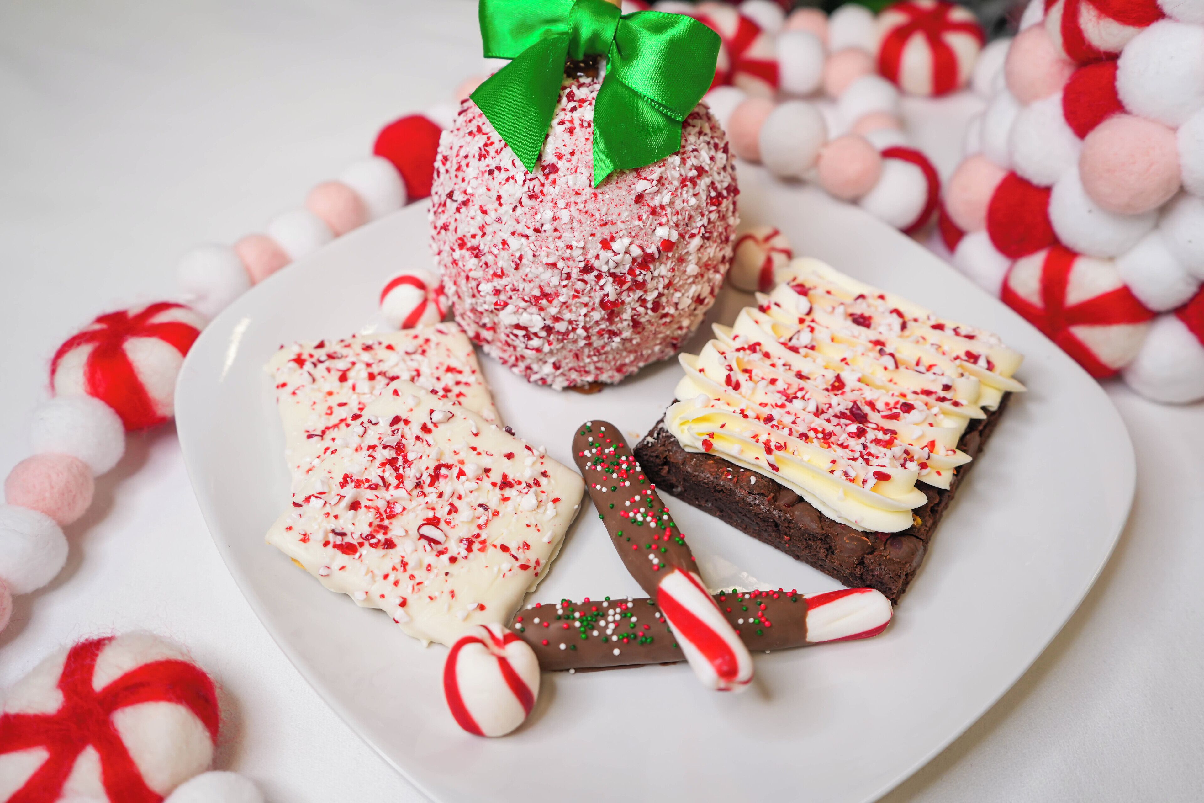 A plate with a chocolate-covered treat, a slice of cake, and a candy cane.