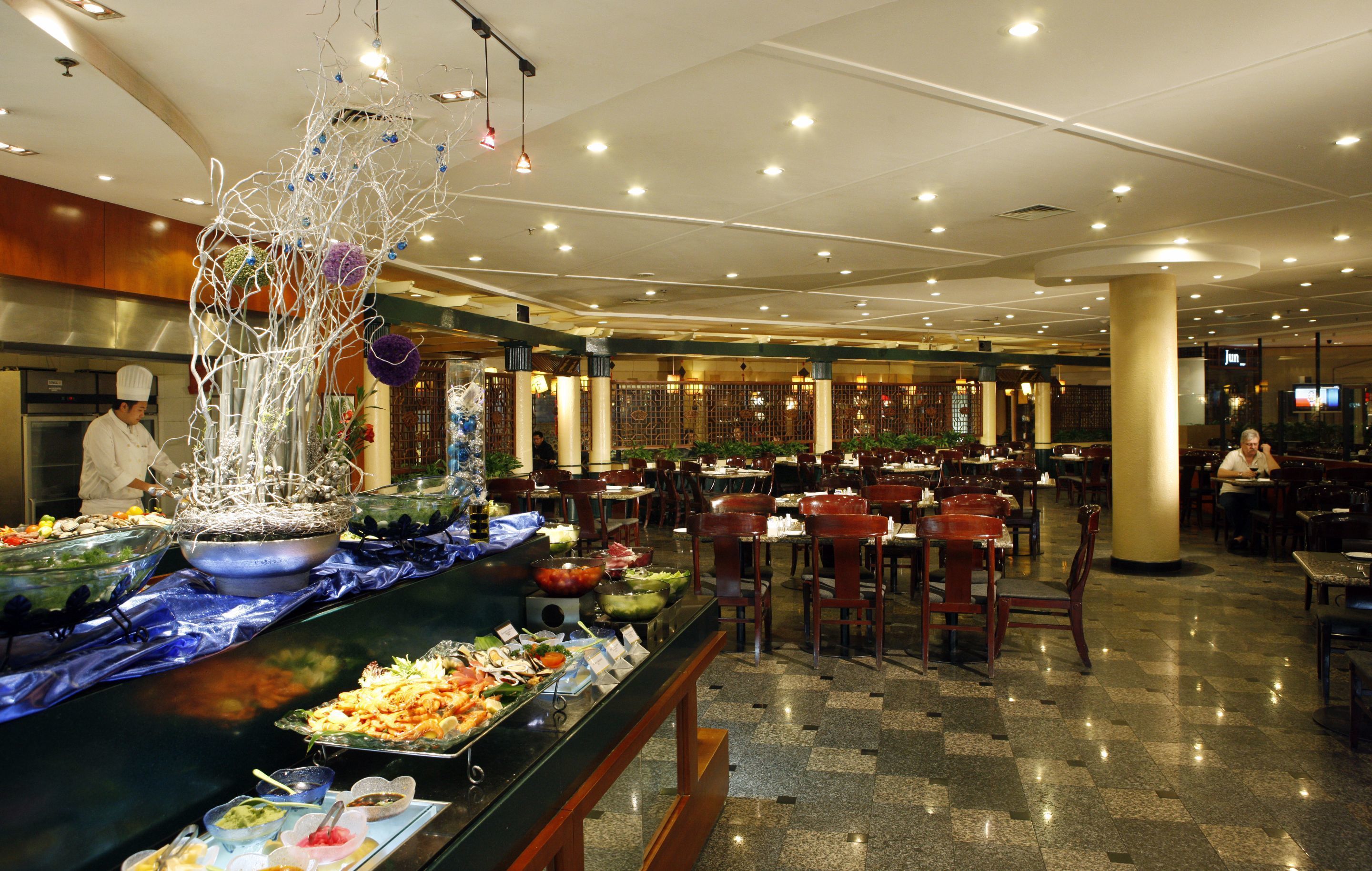 A buffet area with various food stations and a chef preparing food.