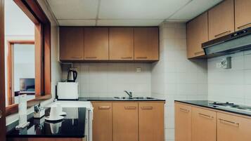 A kitchen with wooden cabinets, a black countertop, a sink, and a coffee maker.