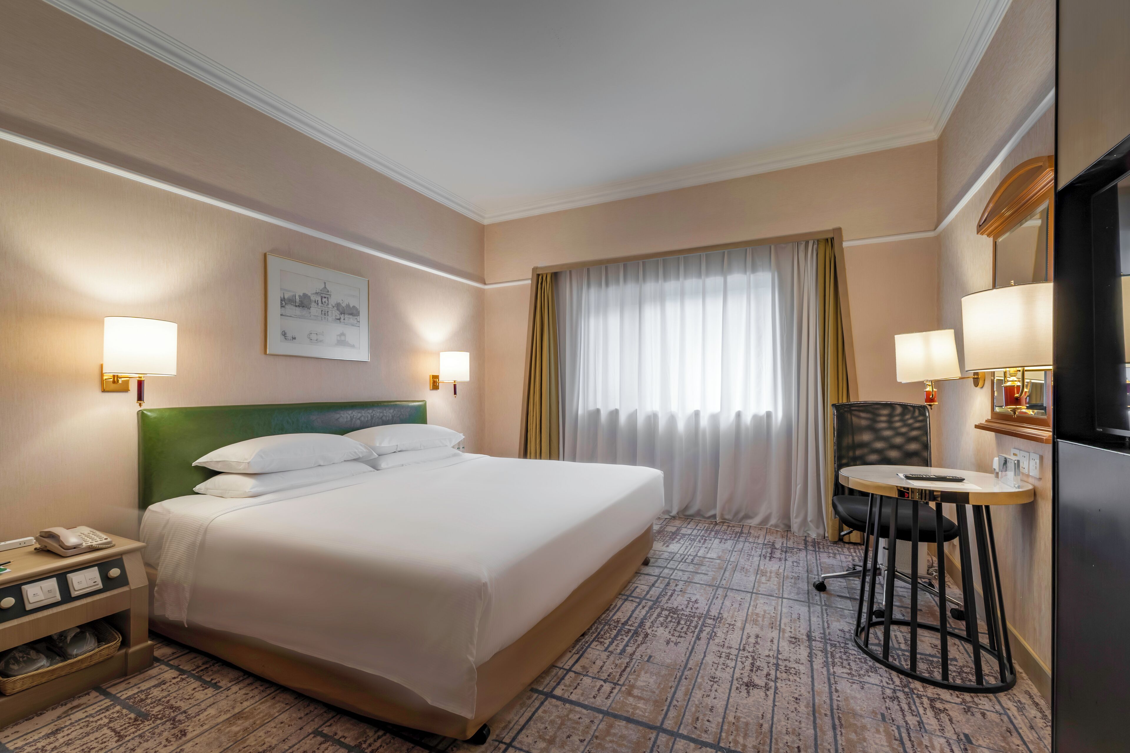 Ein Hotelzimmer mit einem großen Bett, einem Schreibtisch mit Stuhl, einem Telefon und einem Fenster mit Vorhängen.