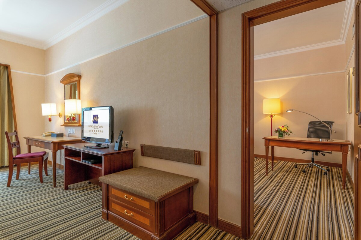 Habitación de hotel con cama, escritorio, silla y espejo.