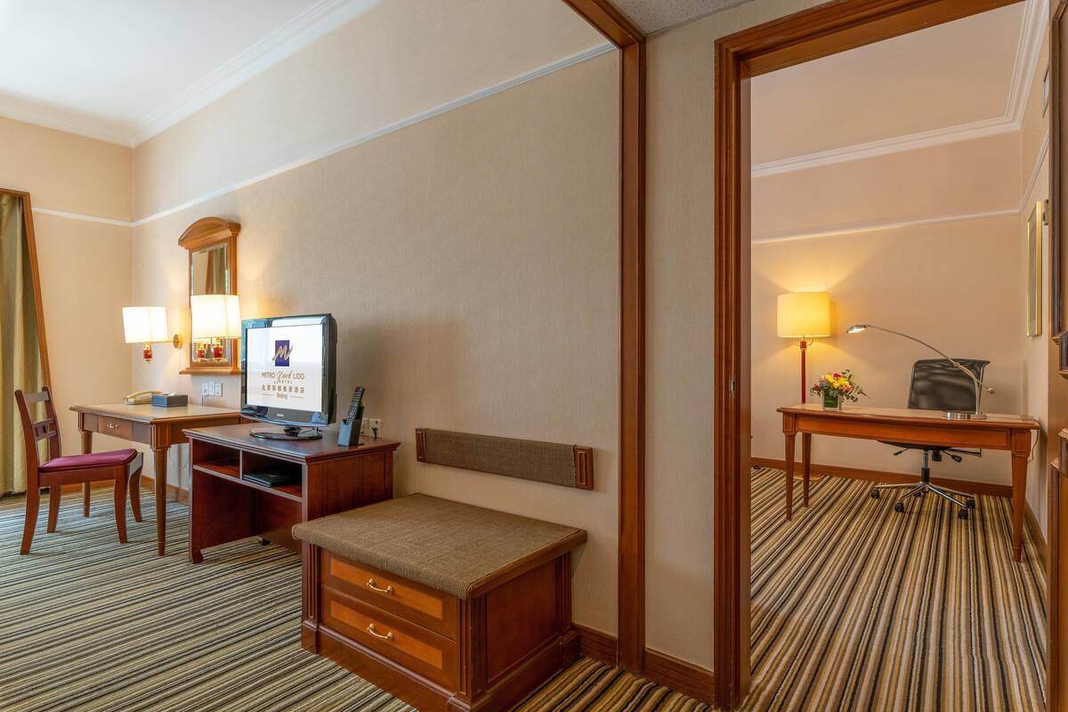 A hotel room with a bed, desk, chair, and a mirror.