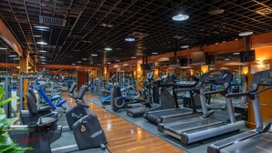 Un gimnasio con diverso equipo de ejercicio, incluyendo cintas de correr y máquinas de pesas, dispuesto en filas.