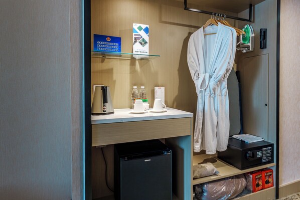 A hotel room with a minibar, a coffee maker, a microwave, and a robe hanging on the door. - Metropark Lido Hotel Beijing (Beijing)