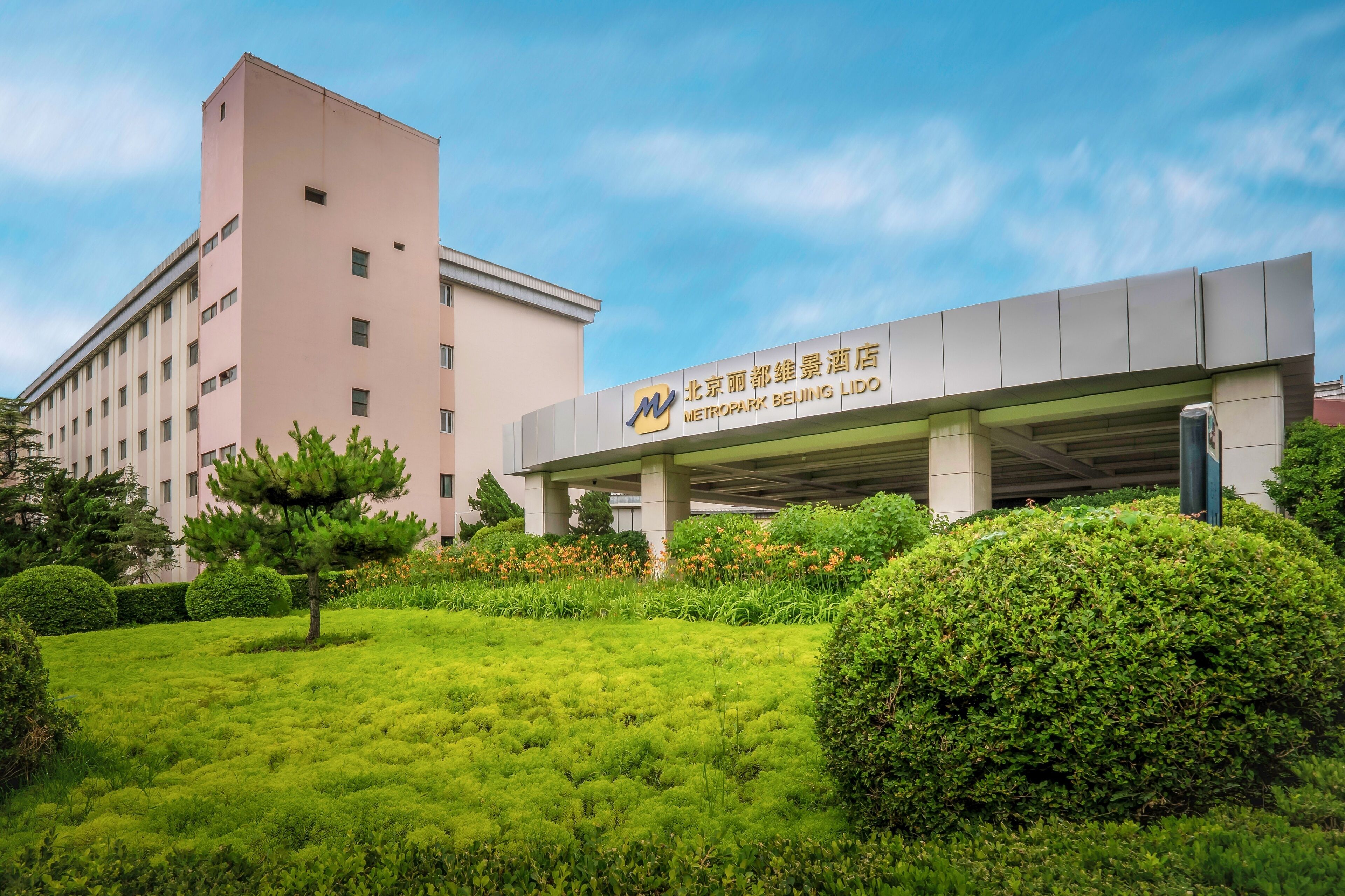 Un hôtel au design moderne, avec une grande enseigne ornée de caractères chinois et un logo.