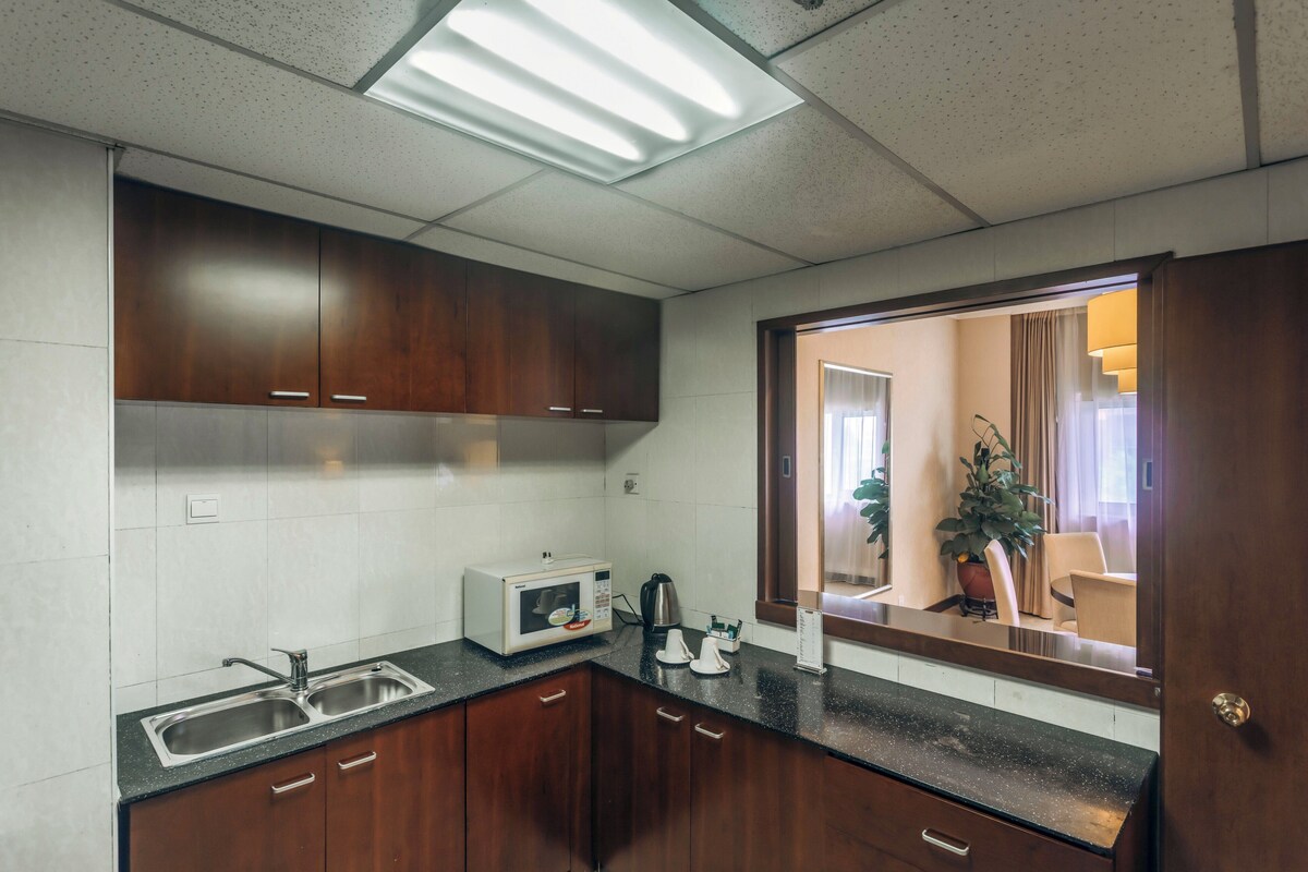 A modern kitchen with stainless steel appliances, wooden cabinets, and a black countertop.