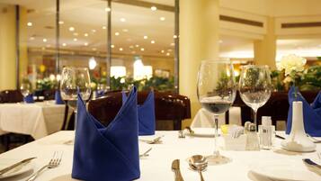 Une table à manger dressée avec des serviettes bleues, des verres à vin et des couverts en argent.