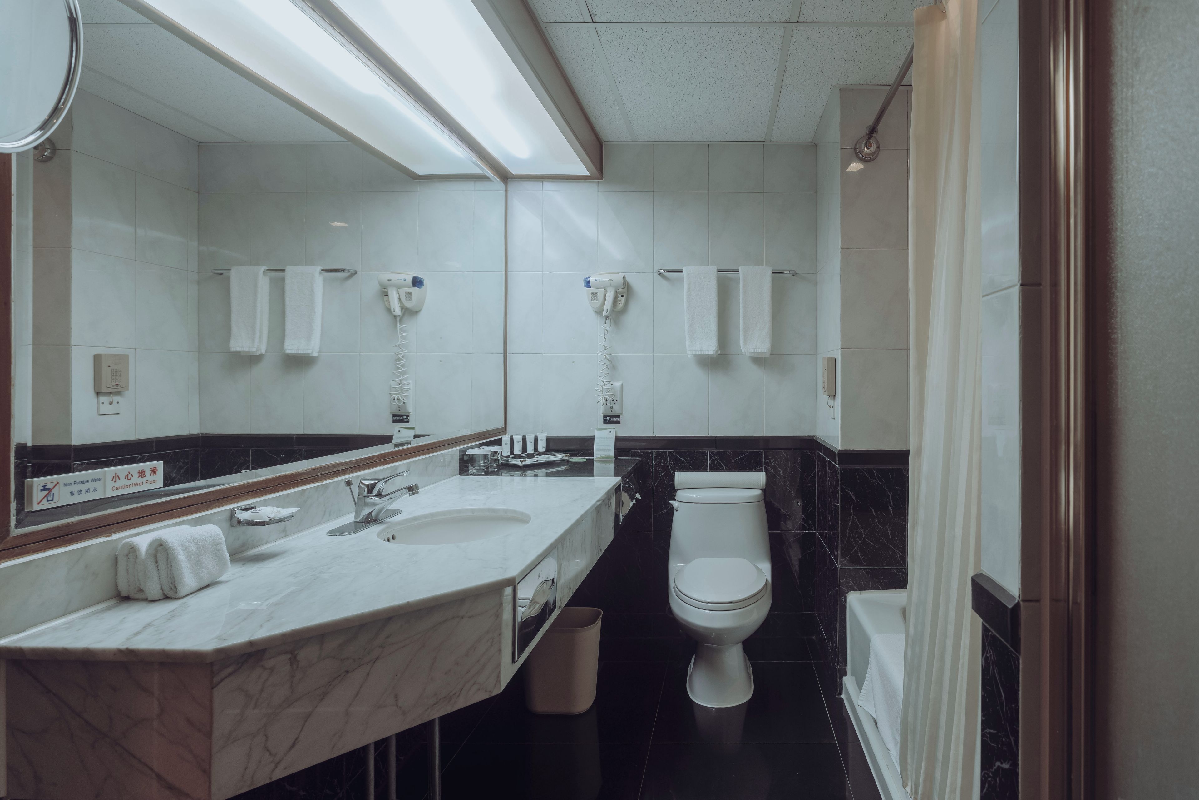 A modern bathroom with a marble sink, two towel racks, a toilet, and a shower area.