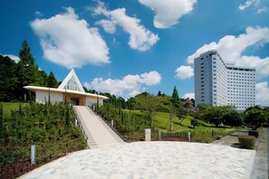 A modern building with a unique triangular roof, a staircase leading to the entrance, and a large parking area.