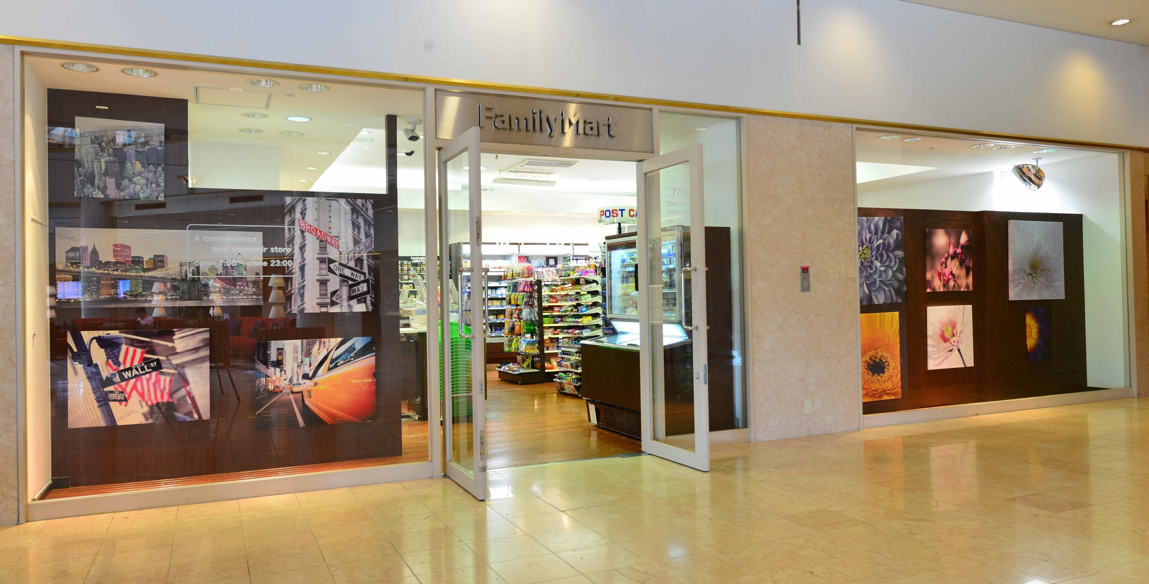 Una tienda FamilyMart con entrada de vidrio, iluminación interior y estantes visibles repletos de productos.