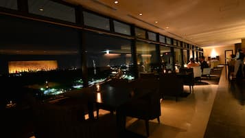 A dimly lit restaurant with a view of the cityscape at night.