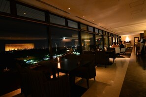 A dimly lit restaurant with a view of the cityscape at night.