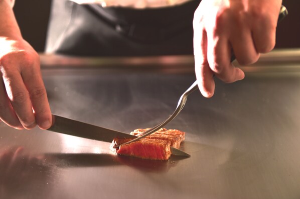 A person cutting a piece of meat on a flat surface.