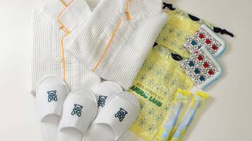 A set of white pajamas with orange trim, a pair of white slippers with bear designs, and a yellow bag with bear patterns.