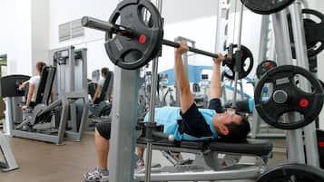 Ein Fitnessraum mit Krafttrainingsgeräten, darunter eine Langhantelbank und verschiedene Gewichte.