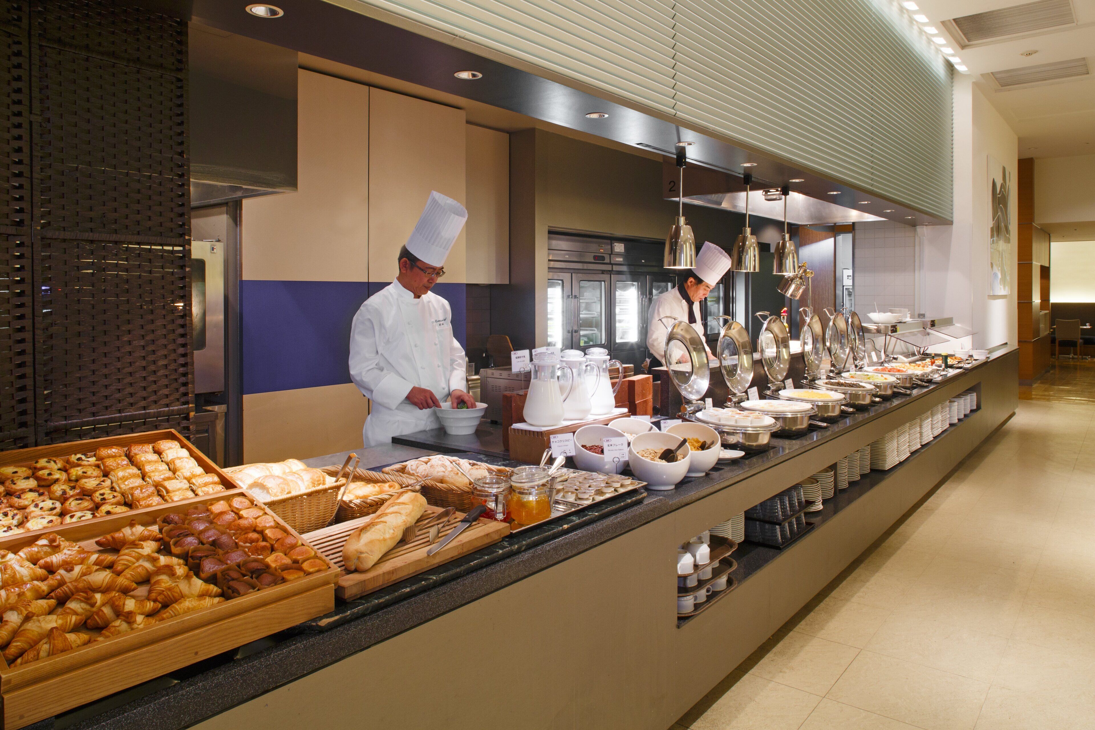 Una mesa de buffet con diversos alimentos y un cocinero preparándolos.