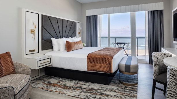 A modern hotel room with a large bed, a desk, and a view of the ocean. - Cirque St. Armands Beachside (Sarasota)