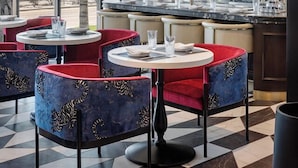 A restaurant with round tables and chairs, large windows, and a view of palm trees. - Cirque St. Armands Beachside (Sarasota)