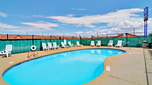 A swimming pool with white lounge chairs and a fenced area. - Motel 6 Lordsburg, NM (Lordsburg)