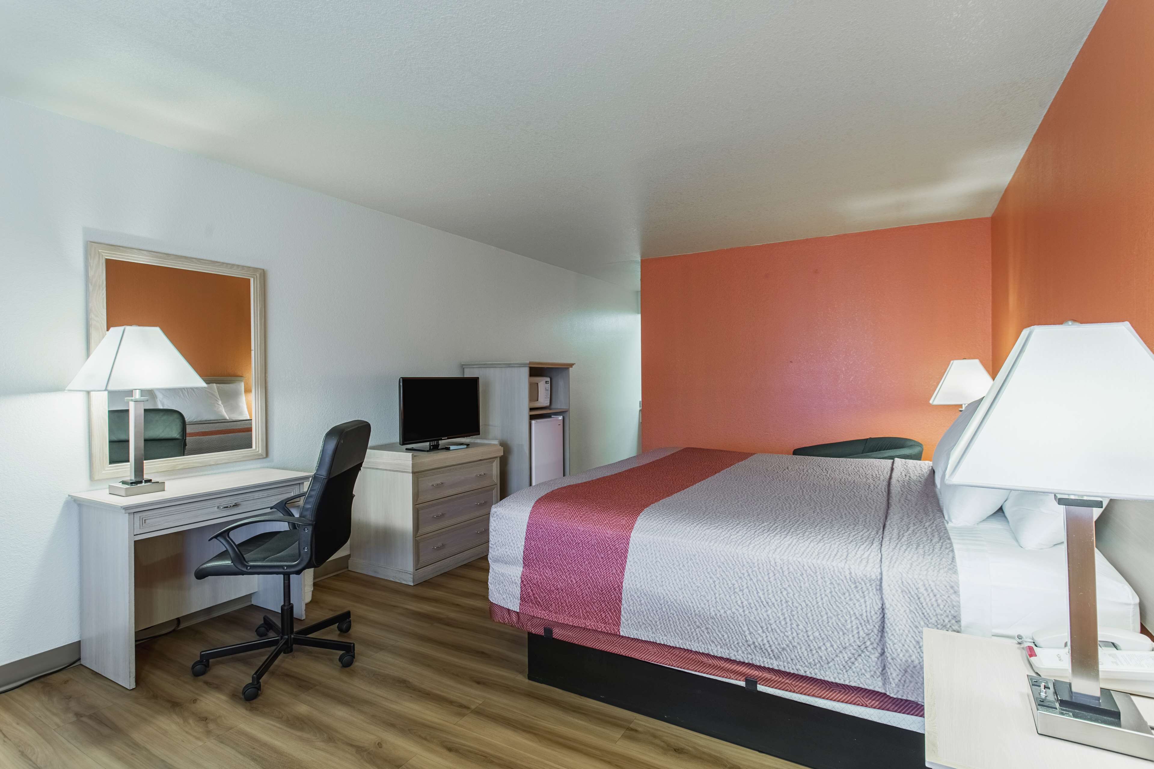 Une chambre d’hôtel équipée d’un lit, d’un bureau, d’une chaise et d’un téléviseur.