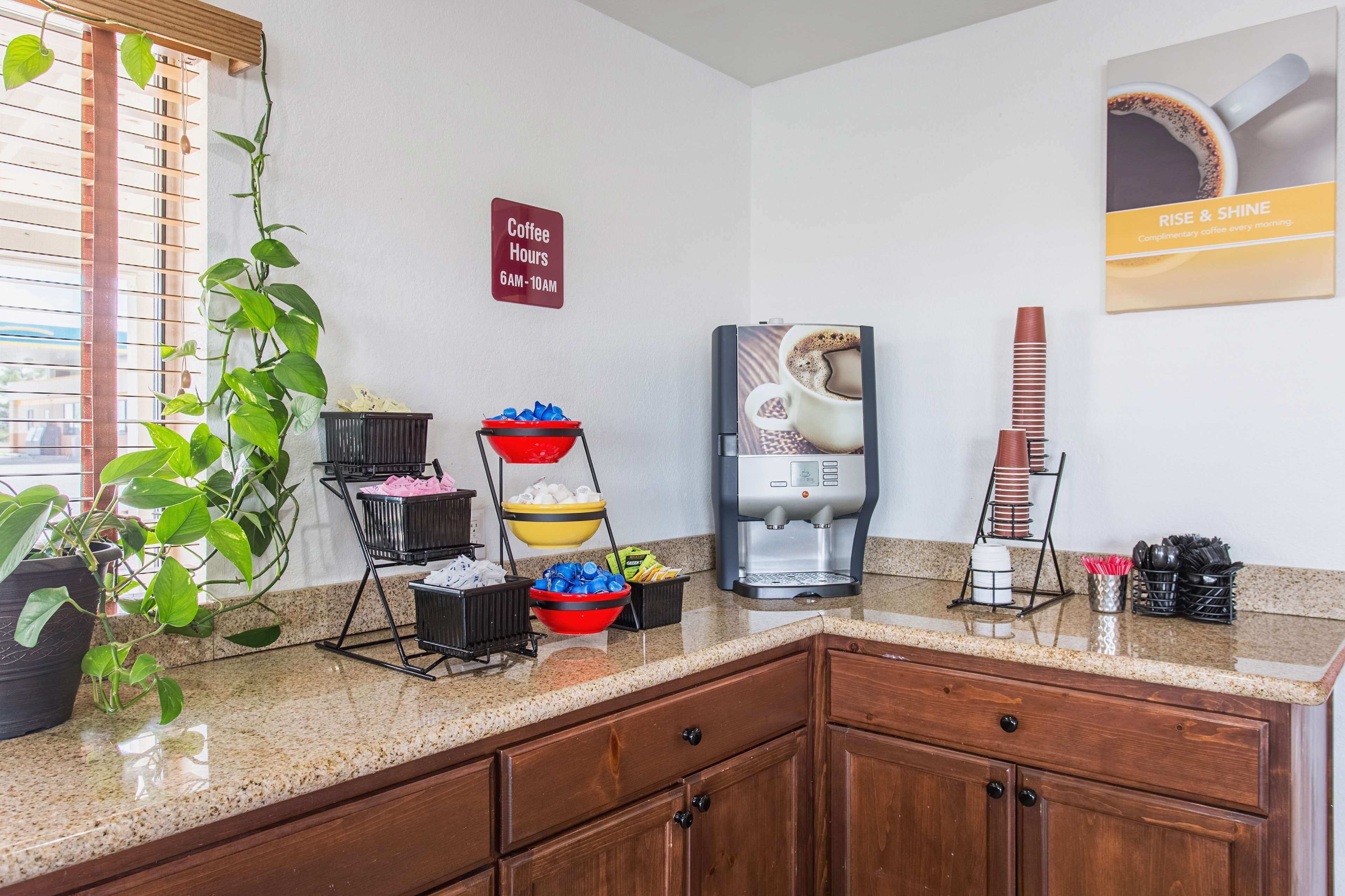 A kitchen area with a coffee station, including a coffee maker, cups, and a sign indicating coffee hours.