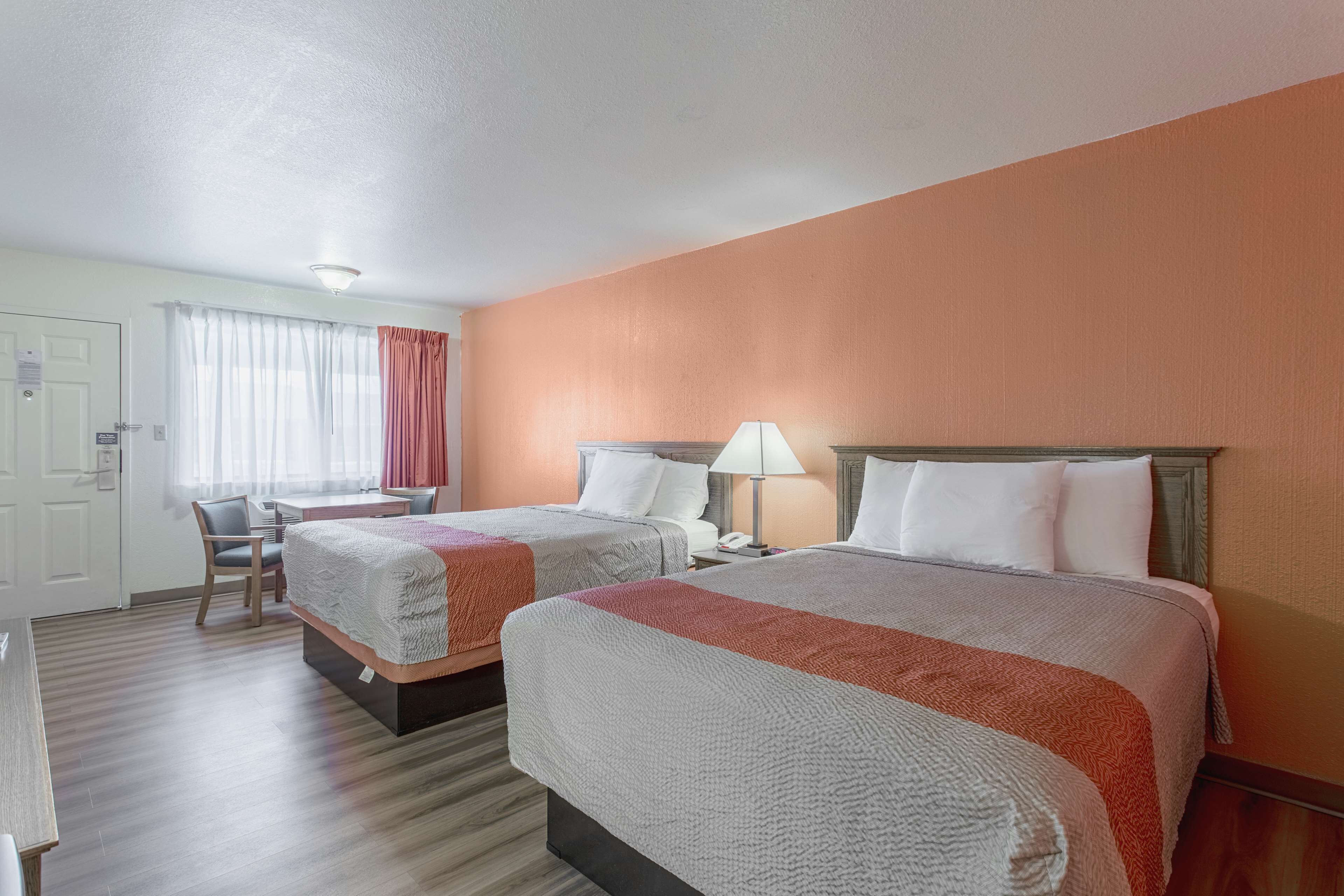 A hotel room with two beds, a desk, and a chair.