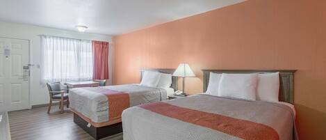 A hotel room with two beds, a desk, and a chair.