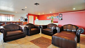 A lobby with leather sofas, a tiled floor, and a red accent wall. - Motel 6 Lordsburg, NM (Lordsburg)
