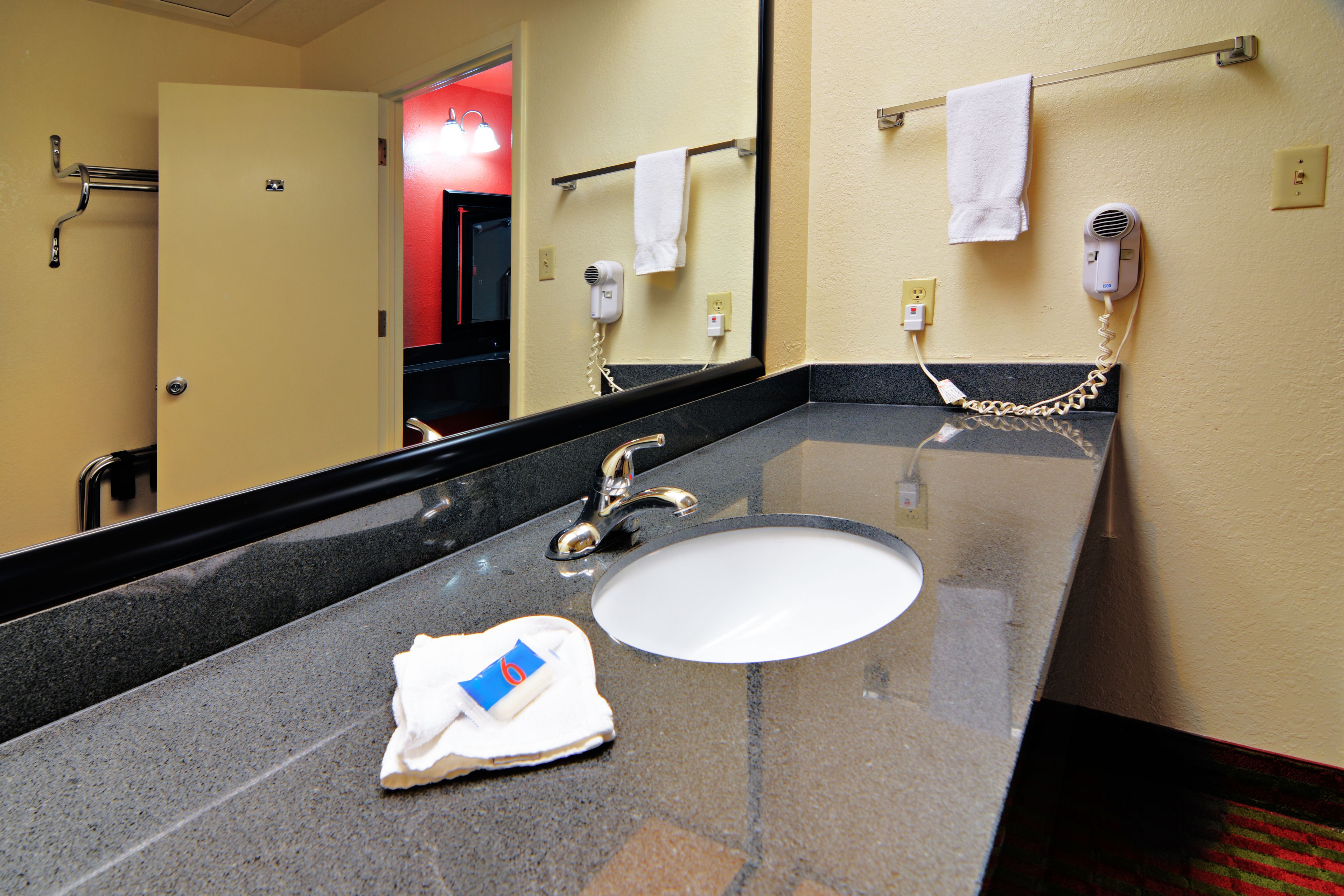 A hotel bathroom with a sink, towel rack, and a hairdryer.