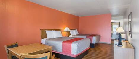 Ein Hotelzimmer mit zwei Betten, einem Holztisch und einem Stuhl.
