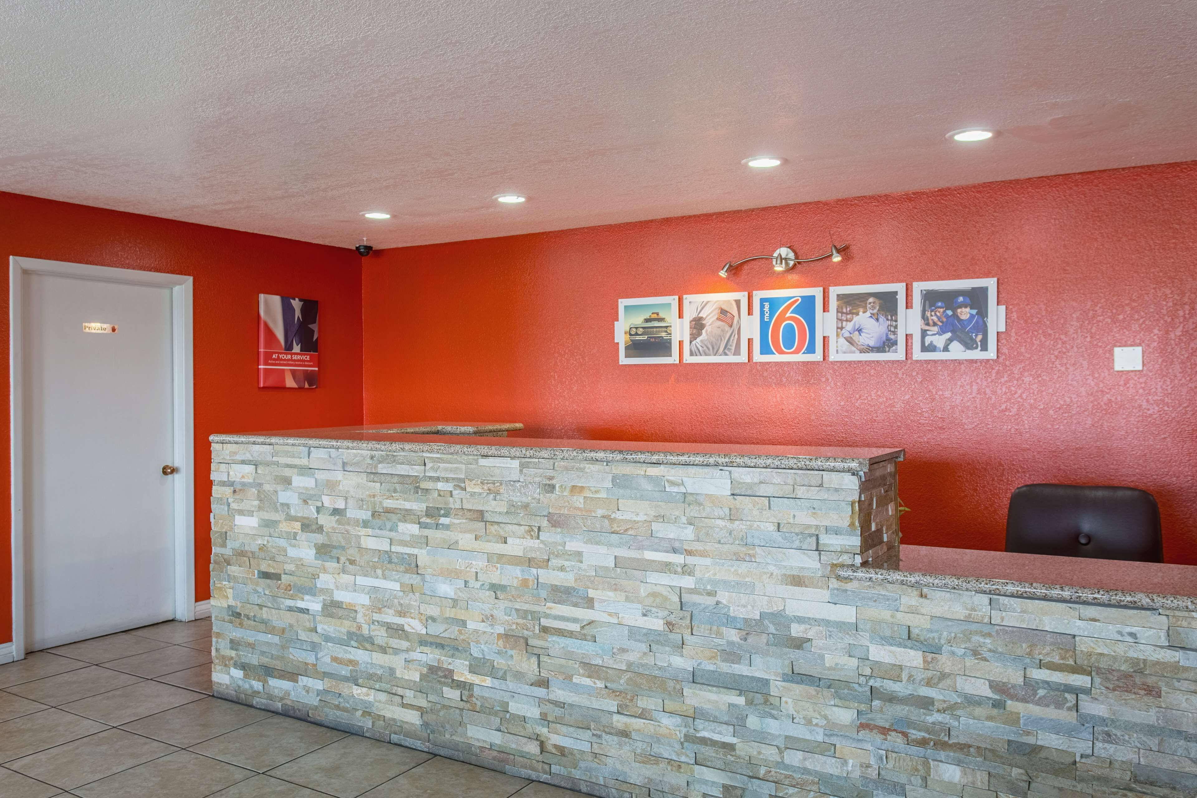 A reception area with a stone counter, a white door, and a red wall with framed pictures.