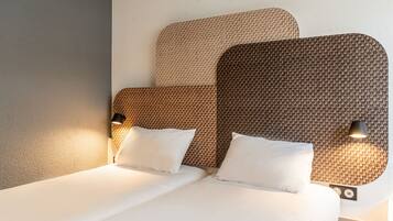 A neatly made bed with white linens and two pillows, a headboard with a woven pattern, and two wall-mounted lamps on either side.
