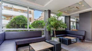 Un espace de détente moderne comprenant un canapé, une table basse et un coin salon offrant une vue sur l’extérieur.