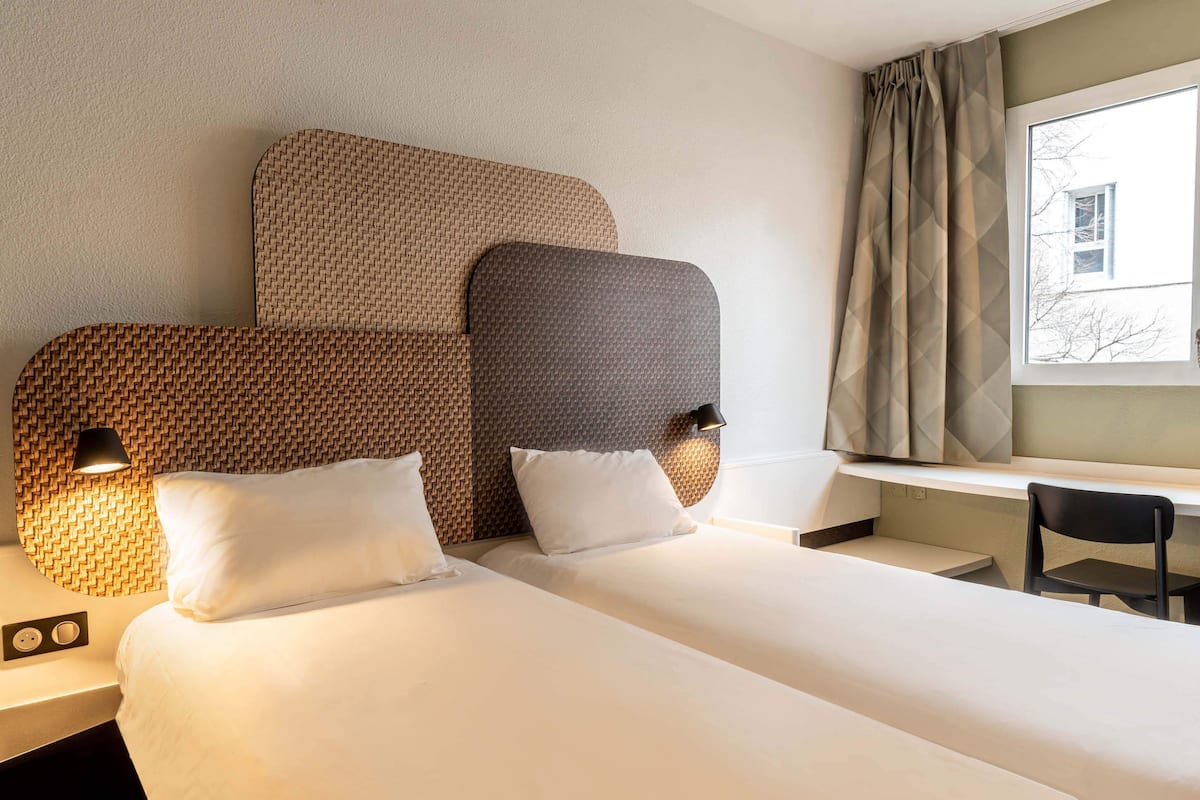 Une chambre d’hôtel avec deux lits, un bureau et une chaise.