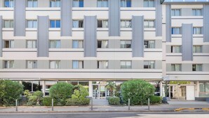 Un hôtel moderne à la façade symétrique, doté de nombreux balcons et d’une entrée centrale.