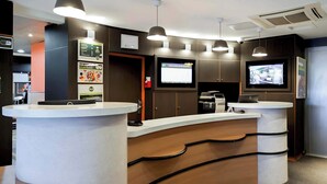 Un espace d’accueil moderne comprenant deux comptoirs de réception, un éclairage au plafond, un écran numérique et un téléviseur.