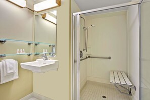 A bathroom with a glass shower enclosure, a sink with a mirror, and a towel rack. - Travelodge by Wyndham Presidio San Francisco (San Francisco)