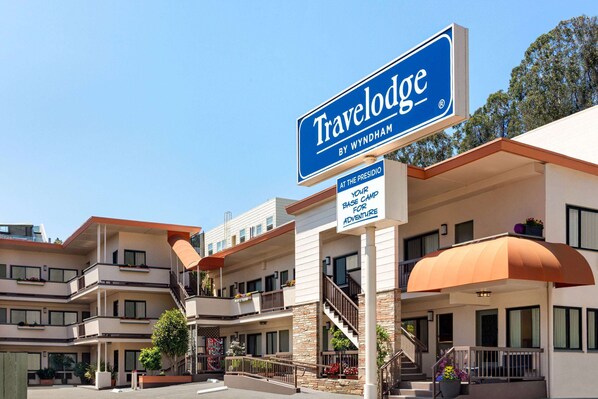 A Travelodge by Wyndham hotel with multiple balconies, outdoor seating, and a clear sky. - Travelodge by Wyndham Presidio San Francisco (San Francisco)