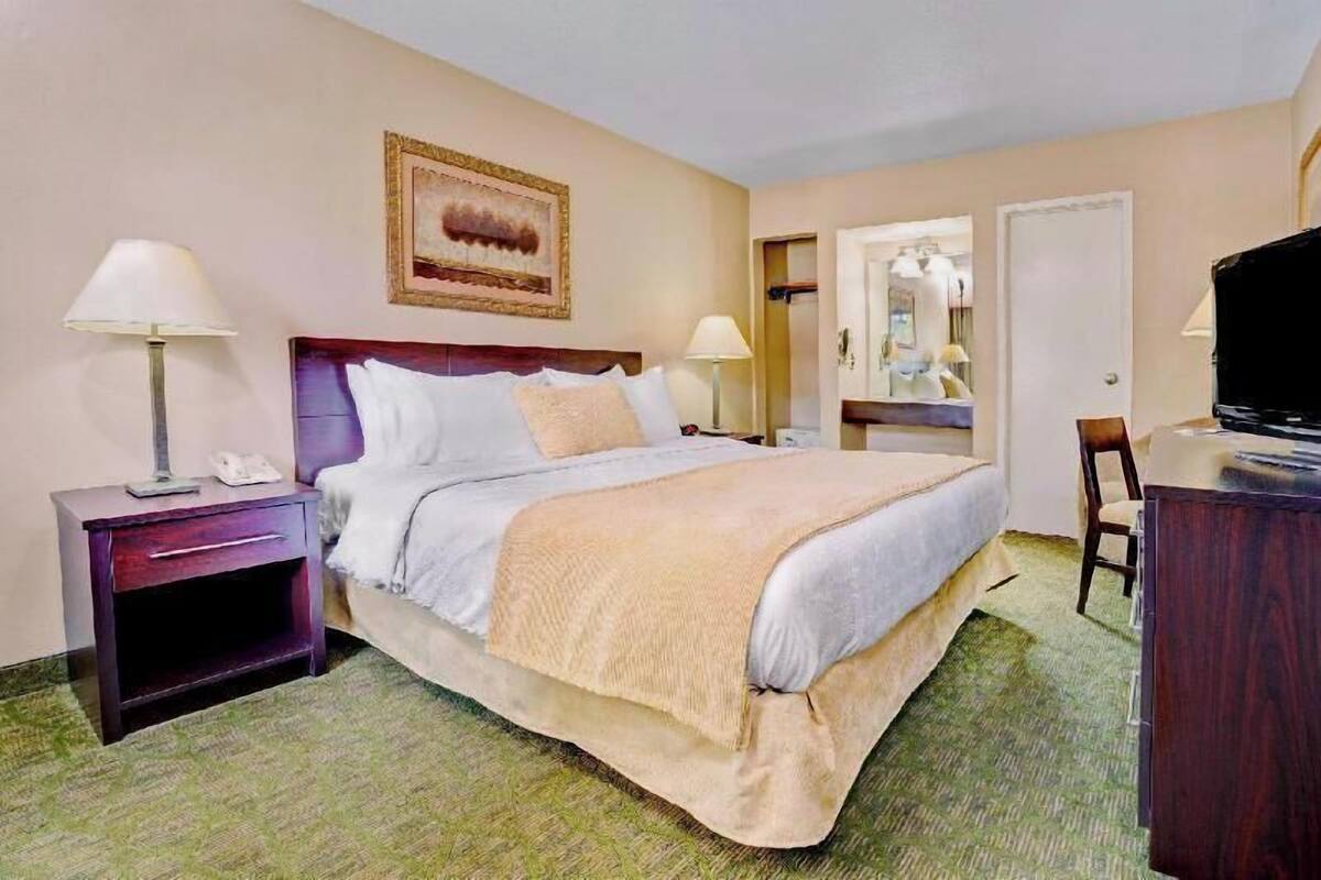 Een hotelkamer met een bed, bedlampen, een bureau, een televisie en een spiegel.
