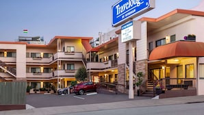 Een Travelodge hotel met meerdere balkons, een vlag en een bord waarop staat dat het een startpunt is voor avontuur.