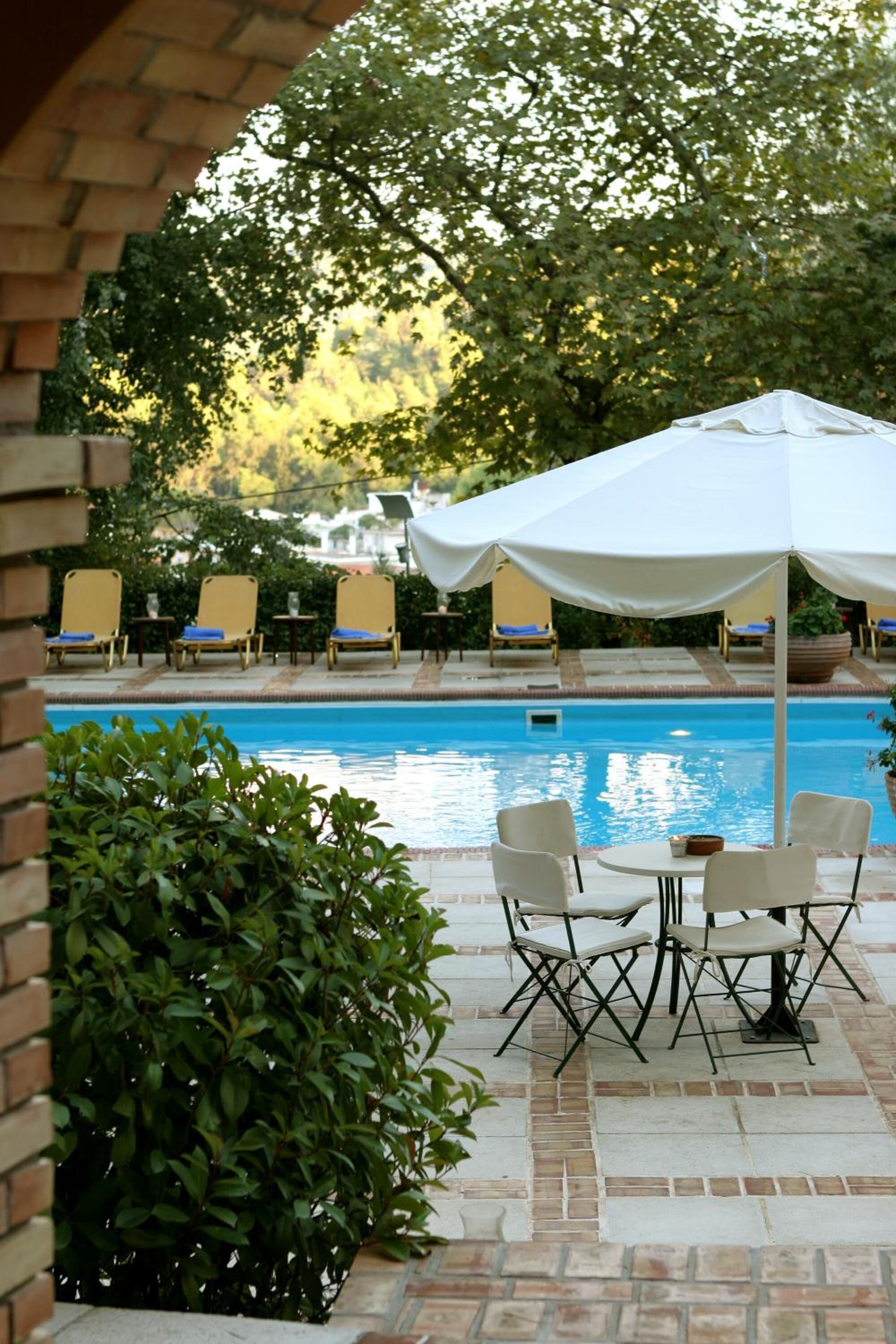 Un espace aménagé au bord de la piscine, avec des chaises longues et une table placée sous un auvent.