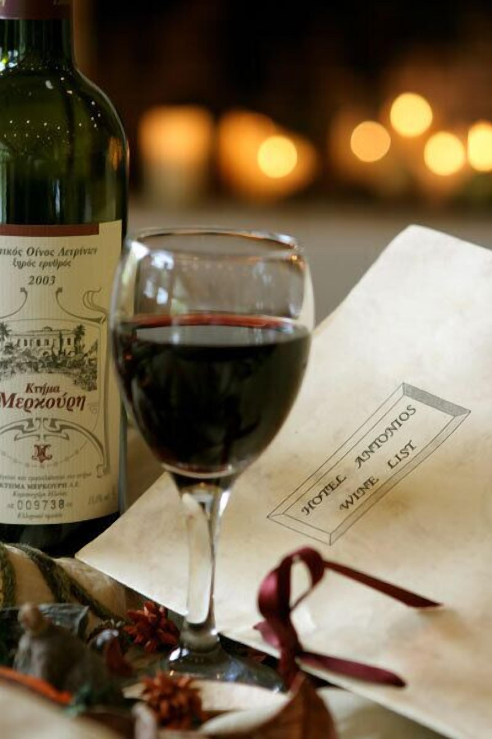 Une bouteille de vin Krivka Mezocheno, un verre de vin rouge et un menu orné d’un ruban rouge.